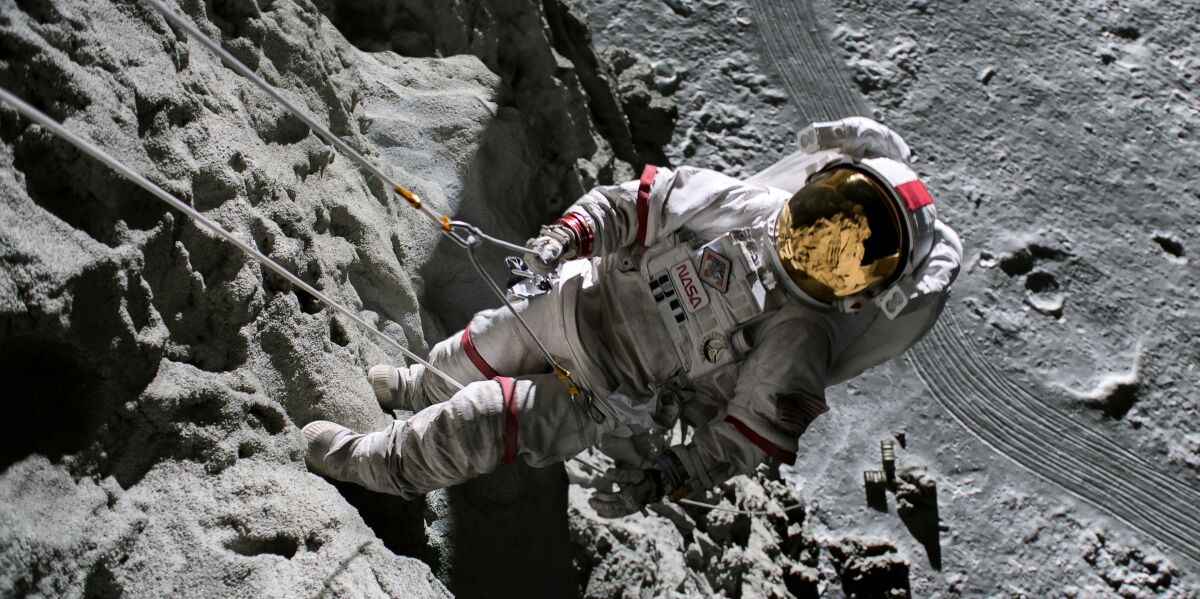 A person in a white spacesuit rappels down a cliff. The landscape is gray.