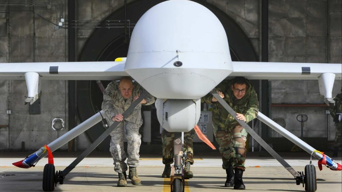 Google recently decided not to renew a contract to use artificial intelligence to analyze drone footage. Above, members of the California National Guard push a Predator aircraft from its hangar at George Air Base in Victorville.