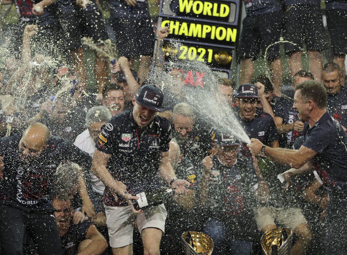 FILE - Red Bull driver Max Verstappen of the Netherlands, left, celebrates with Red Bull team chief Christian Horner, right, and his team in the pit lane after becoming F1 driver world champion after winning the Formula One Abu Dhabi Grand Prix in Abu Dhabi, United Arab Emirates, Dec. 12. 2021. The Red Bull Formula One team has secured a new title sponsorship worth around $500 million with technology firm Oracle, placing it among the most lucrative commercial deals in sports. The five-year deal is a lift to the team ahead of the season beginning next month when Max Verstappen will be looking to defend his world title in a new Oracle Red Bull Racing car that was also revealed on Wednesday Feb. 9, 2022. (AP Photo/Kamran Jebreili, File)