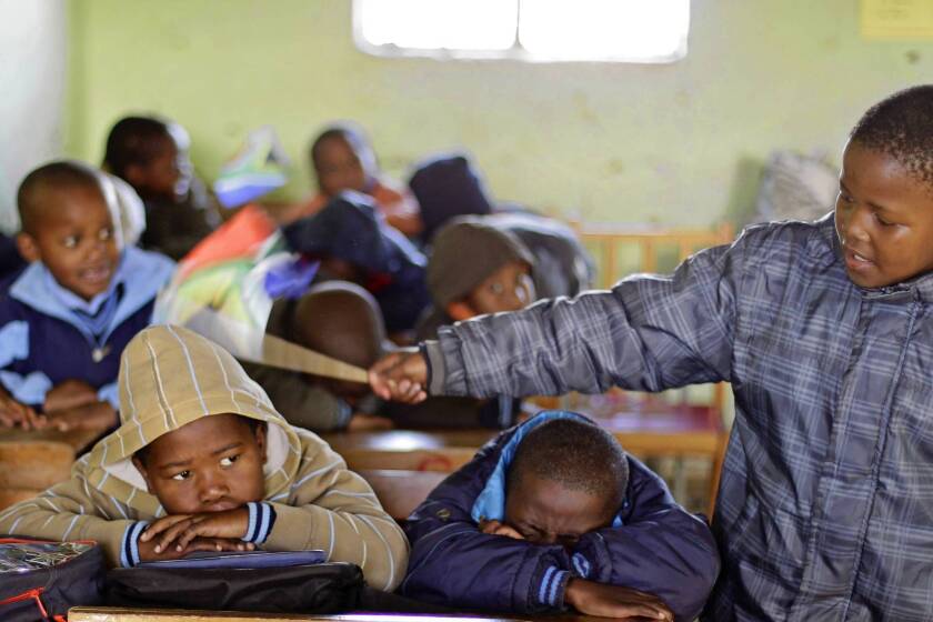 A boy keeps control over fellow students by tapping them with a South African flag at a school in Qunu.