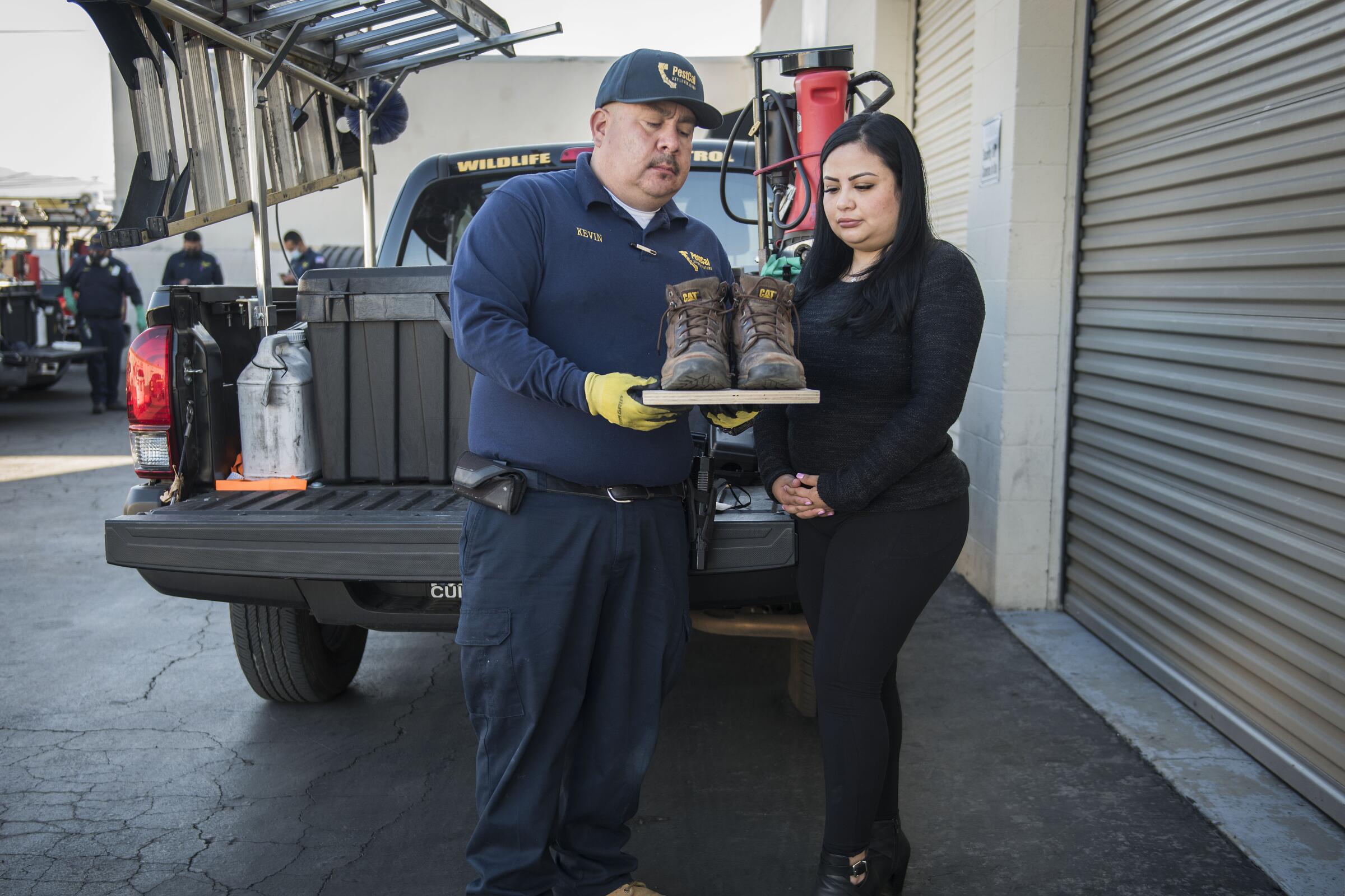 Kevin and Nidia Campos hold the boots of the late Sergio Ayala.