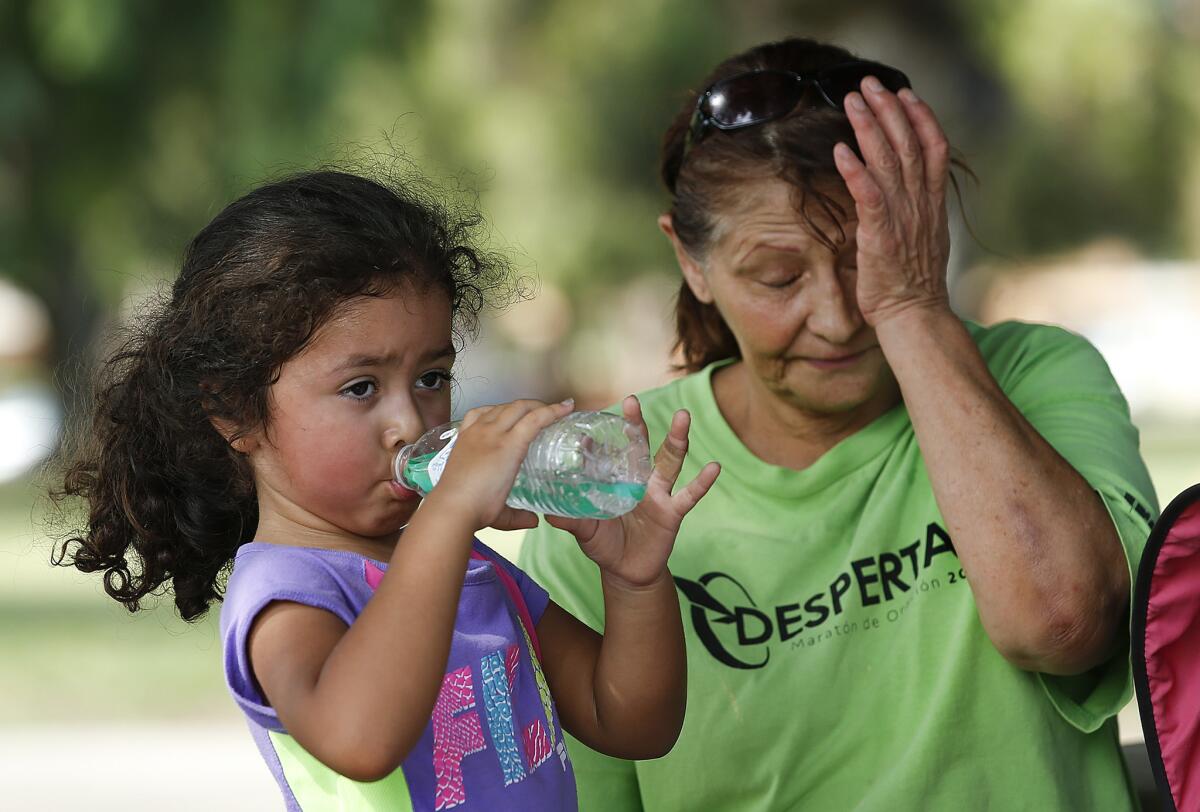Lilly Santiago, 5, left, cools off with her mother, Lupita, 56, after playing basketball at Lanark Park on Thursday.