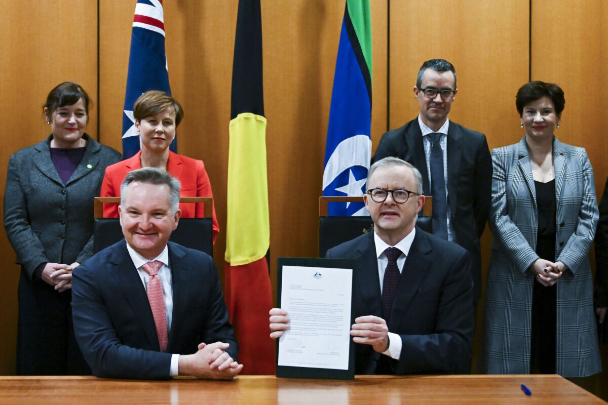 Australian Prime Minister Anthony Albanese, front right, and Australian Minister for Climate Change Chris Bowen pose for photographs after signing the Nationally Determined Contribution to a cut in emissions by 2030 at Parliament House in Canberra, Australia, Thursday, June 16, 2022. Australia’s new government on Thursday formally committed to a more ambitious greenhouse gas reduction target of 43% by the end of the decade in fulfillment of a key election pledge. (Lukas Coch/AAP Image via AP)