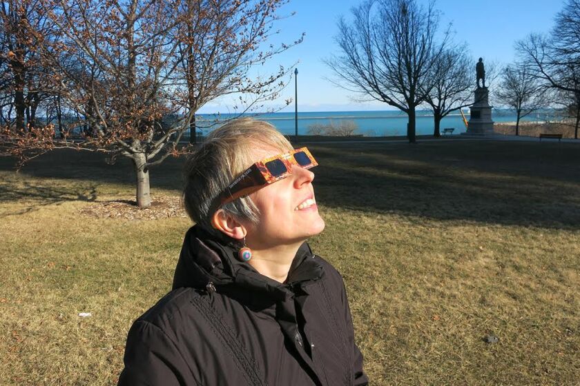 Holley Bakich observes the sun safely through approved solar glasses. These glasses, available from RainbowSymphony.com, cost $2 each, and less in quantity.
