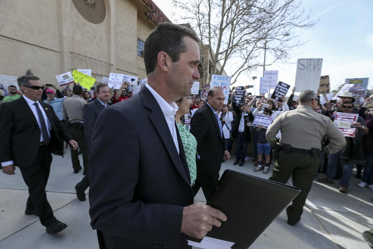Rep. Steve Knight (R-Lancaster) walks past protesters as he leaves after holding a town hall meeting on Saturday in Palmdale.