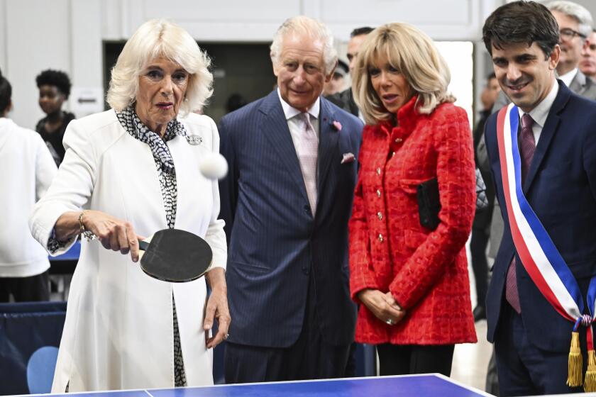 Britain's Queen Camilla plays table tennis as Britain's King Charles III, French President Emmanuel Macron's wife Brigitte Macron, and mayor of Saint-Denis Mathieu Hanotin, right, during a visit to a gymnasium, Thursday, Sept. 21, 2023 in Saint-Denis, outside Paris. (Bertrand Guay, Pool via AP)