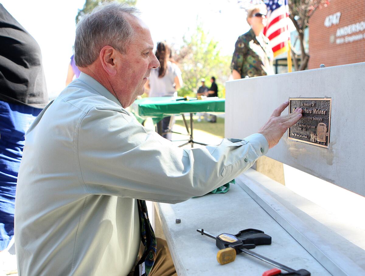 Clark Magnet High School Principal Doug Dall puts final touches onto a placque that was epoxied to a bench during a bench dedication for Barbara Melone at Clark Magnet High School in Glendale on Wednesday, April 30, 2014. Melone a senior administrative secretary at the school, died at the beginning of the school year, and the bench was placed in her honor.