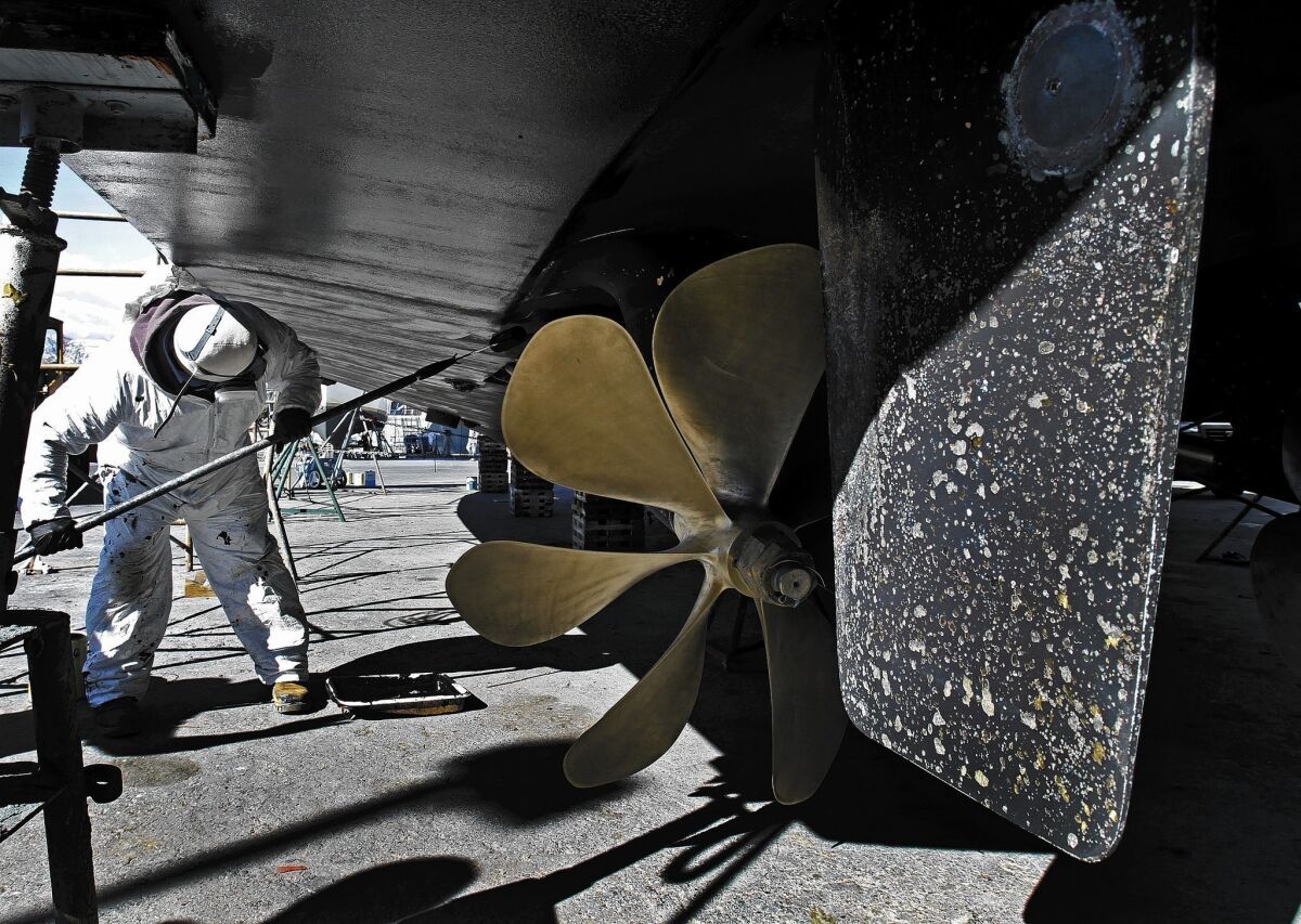 A worker paints the hull of a yacht at Marina del Rey Harbor, where officials are considering a plan that would require boaters to stop using copper paint.