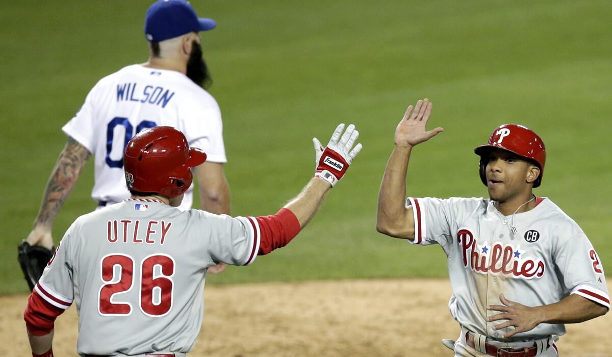 Phillies center fielder Ben Revere is greeted by second baseman Chase Utley after scoring on a two-run double by catcher Carlos Ruiz off Dodgers reliever Brian Wilson in the ninth inning Thursday night at Dodger Stadium.