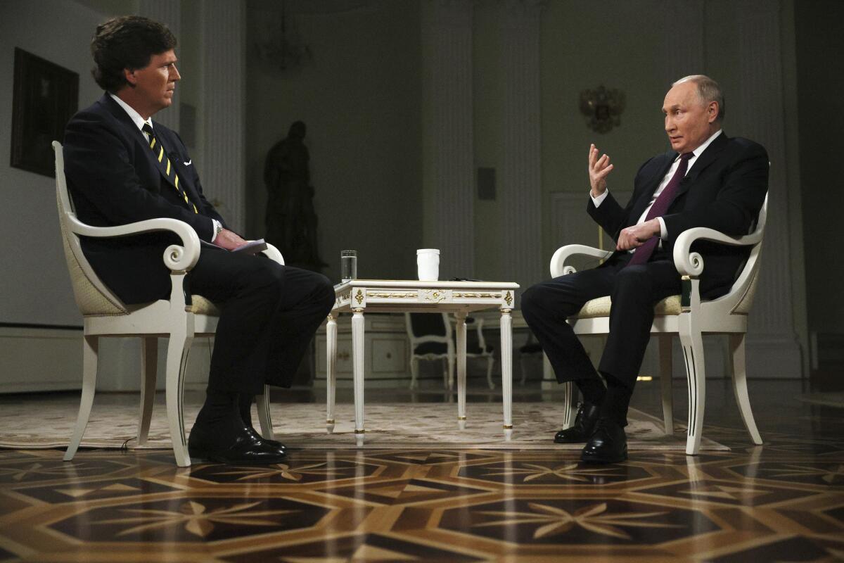 Vladimir Putin, right, sits for an interview with Tucker Carlson