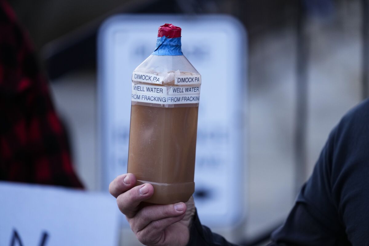 Craig Stevens holds a bottle of brown water as he speaks with members of the media outside the Susquehanna County Courthouse in Montrose, Pa., Tuesday, Nov. 29, 2022. Pennsylvania's most active gas driller has pleaded no contest to criminal environmental charges in a landmark pollution case. Houston-based Coterra Energy Inc. entered its plea Tuesday. (AP Photo/Matt Rourke)
