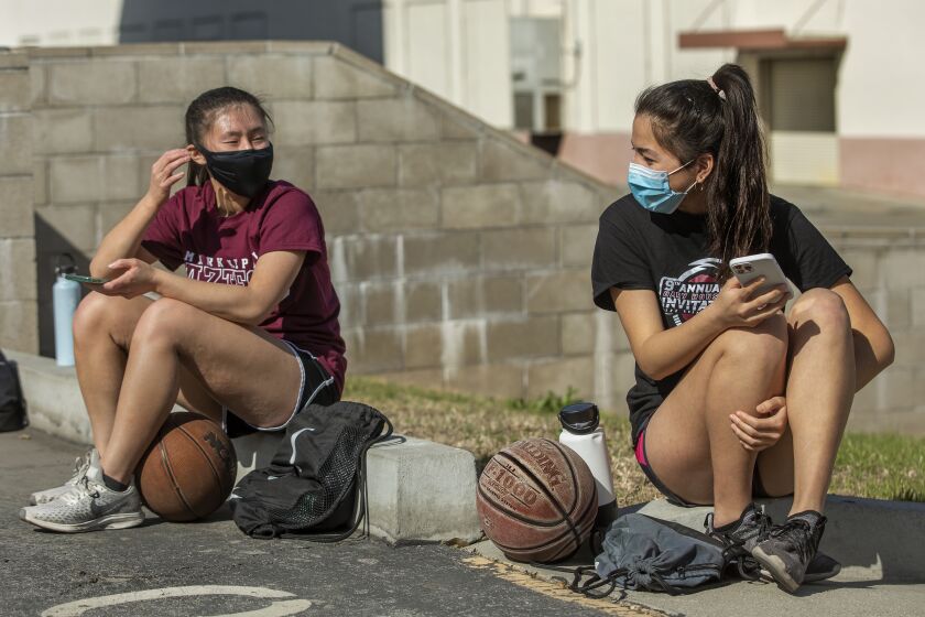 MONTEREY PARK, CA - MARCH 26, 2021: Kendall Tam, left, a senior at Mark Keppel High School and captain of the girls varsity basketball team, talks with Emily Liu, a junior, before start of a practice session at the school in Monterey Park. This was the first week back to practice since a year ago last March when everything came to a halt due to the coronavirus outbreak. (Mel Melcon / Los Angeles Times)