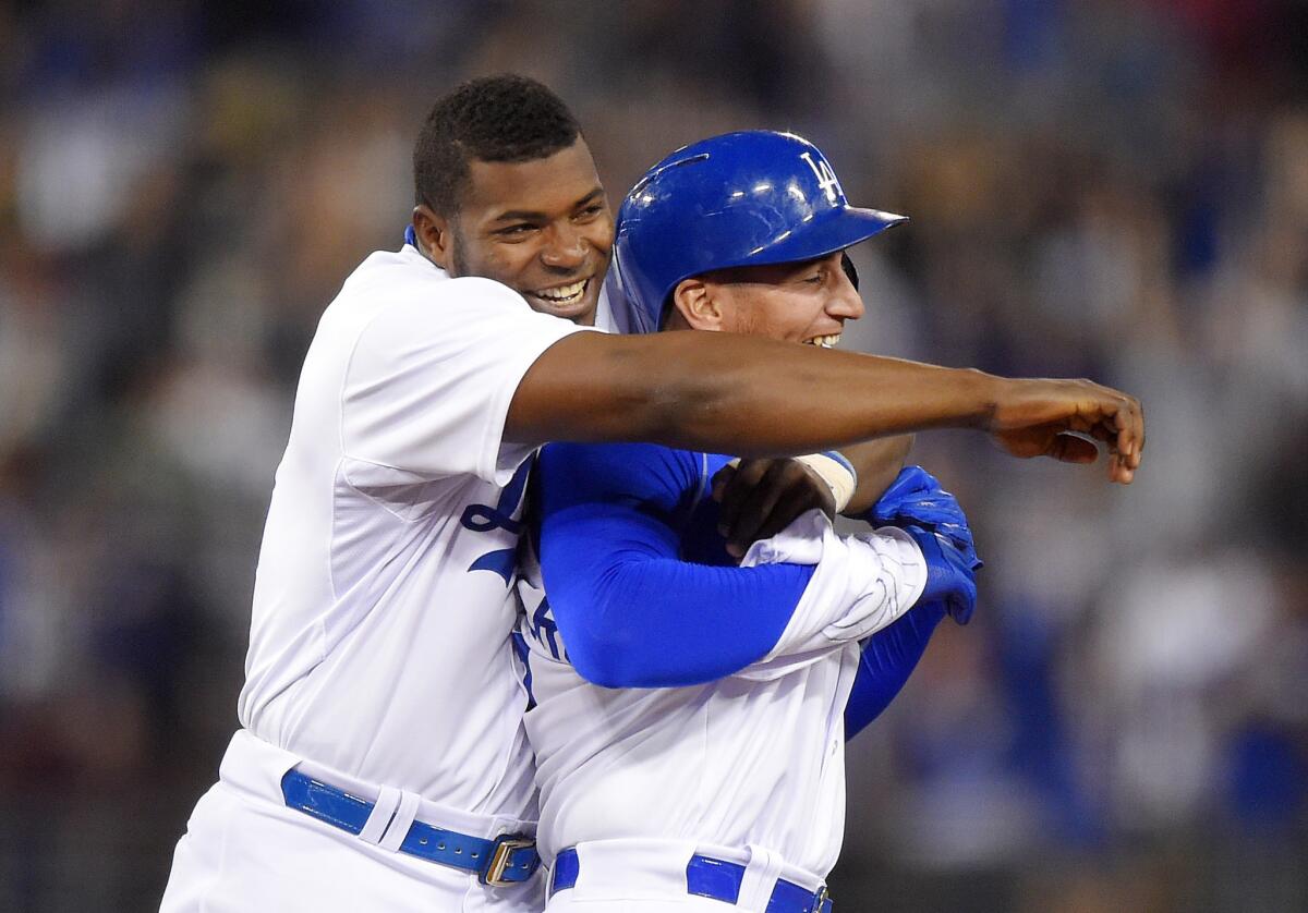 Dodgers outfielder Yasiel Puig, left, hugs Alex Guerrero as they celebrate Guerrero's game-winning single during the 10th inning. The Dodgers beat the Mariners 6-5.
