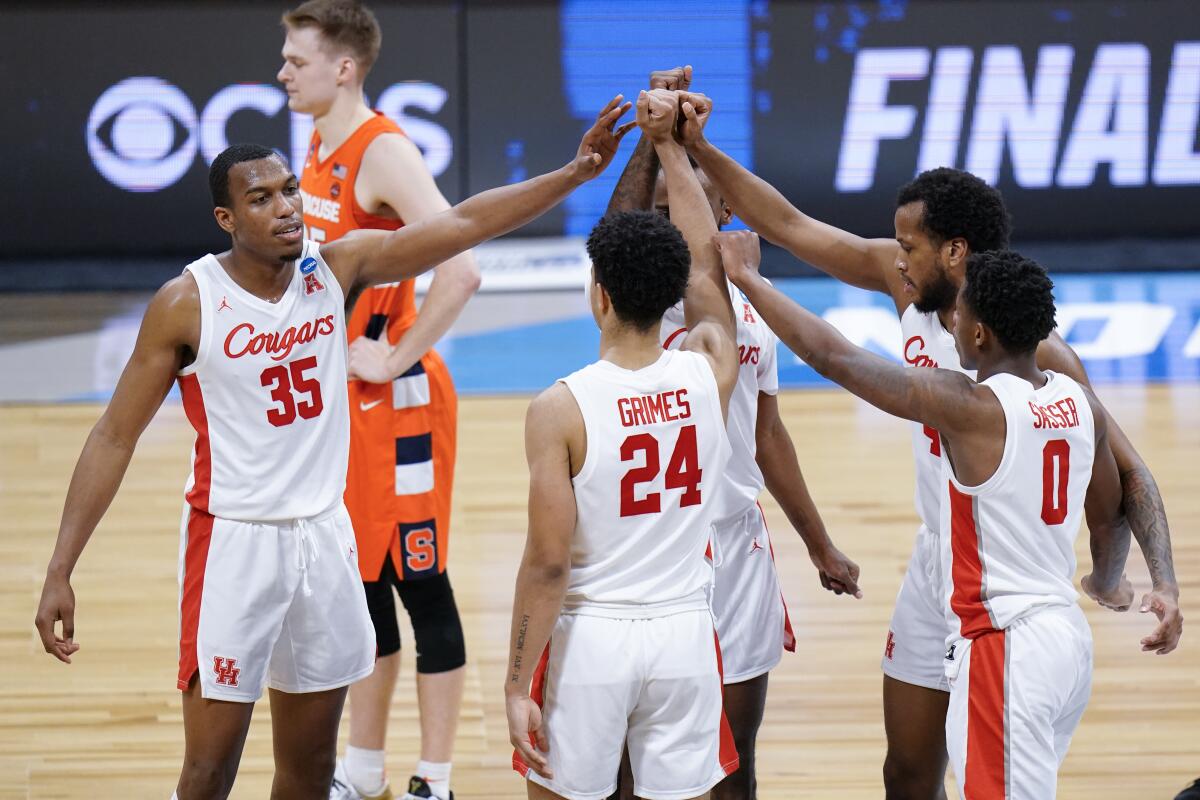 Houston players, including Fabian White Jr. (35), gather as Syracuse's Buddy Boeheim, background, stands by March 27, 2021.