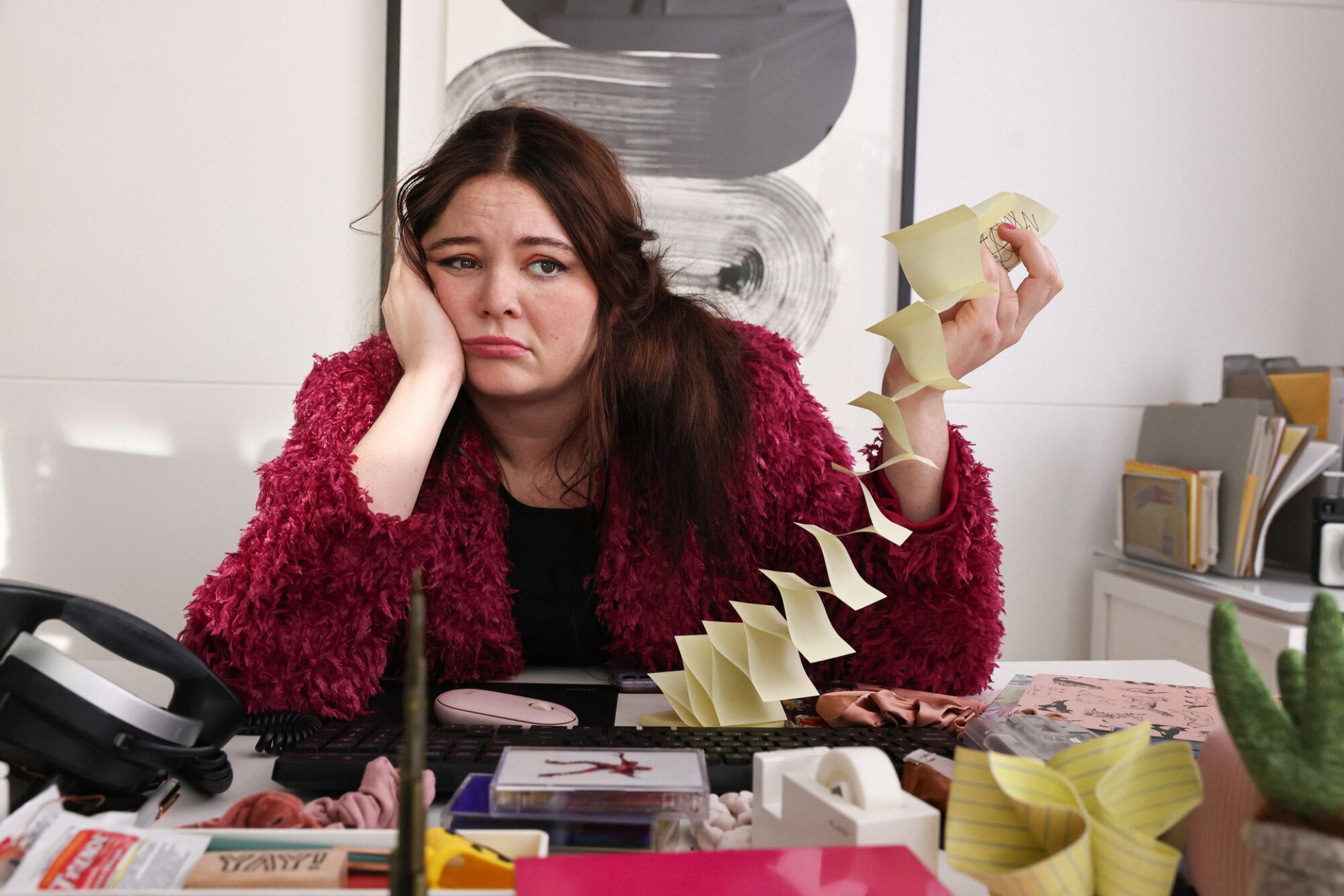 A woman sits at a desk looking miserable.
