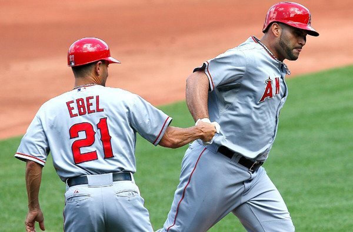 Angels first baseman Albert Pujols is congratulated by third base coach Dino Ebel after hitting a home run against the Boston Red Sox last weekend.