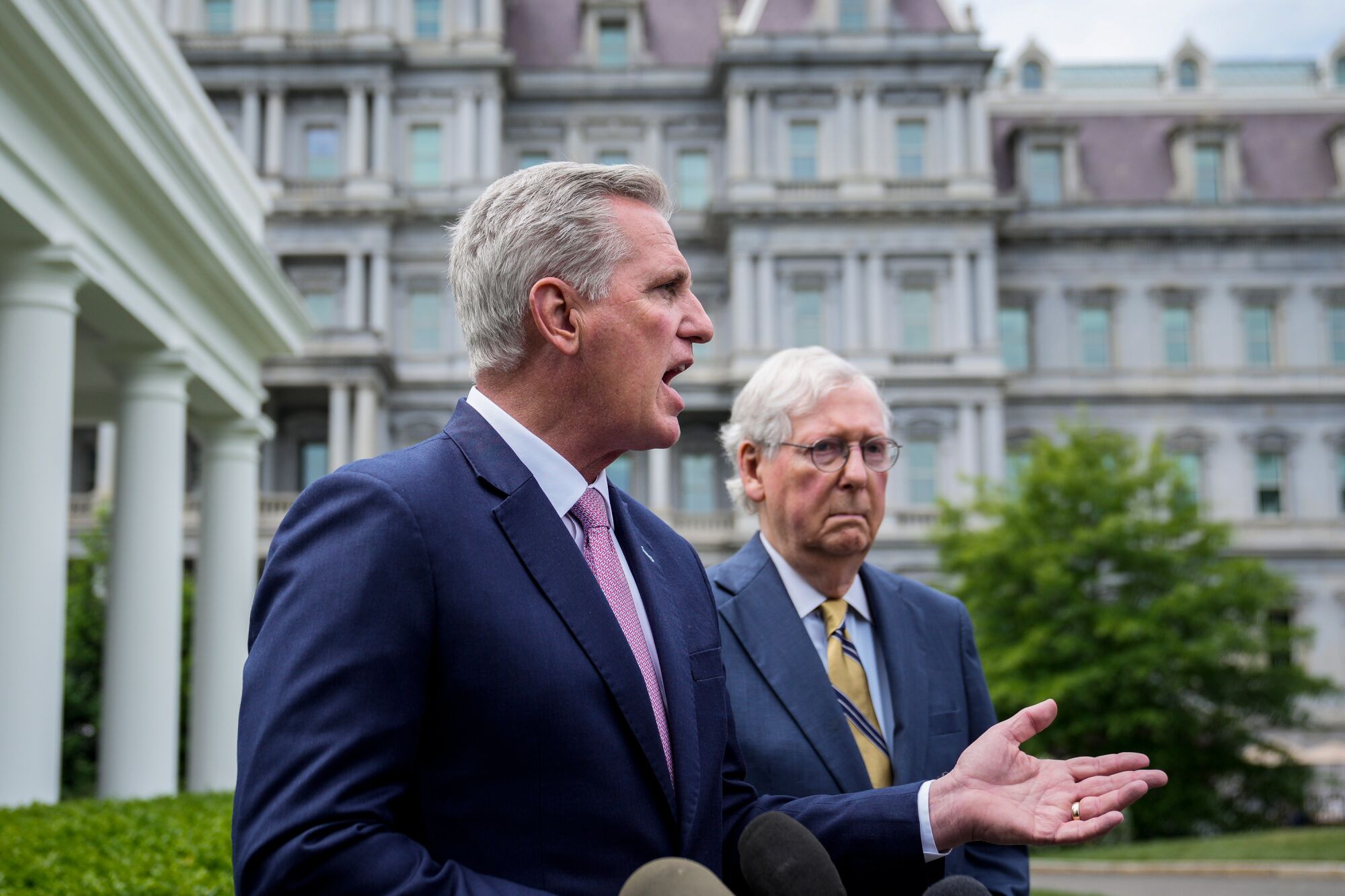 Kevin McCarthy speaks to reporters outside, with Mitch McConnell behind him