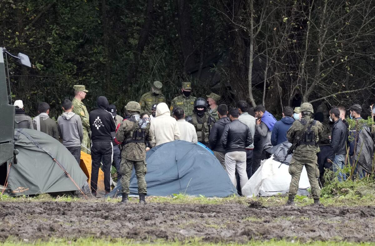 Polish security forces surround migrants stuck along with border with Belarus in Usnarz Gorny, Poland, on Wednesday, Sept. 1, 2021. Poland has been reinforcing its border with Belarus – also part of the EU's eastern border – after thousands of migrants from Iraq, Afghanistan and elsewhere tried to illegally enter the country. The Polish government says it is the target of a "hybrid war" waged by authoritarian Belarus. Human rights activists are concerned about a group caught along the border, trapped between armed guards on each side. (AP Photo/Czarek Sokolowski)