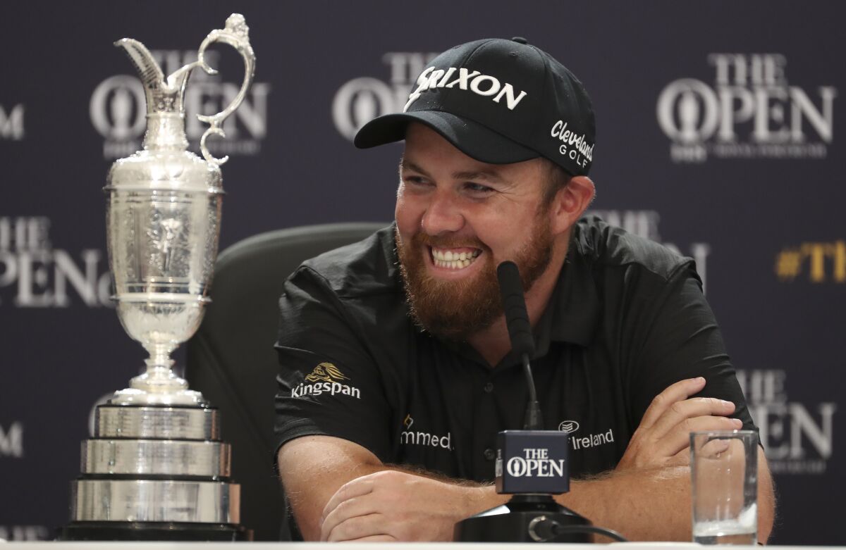 FILE - Ireland's Shane Lowry smiles as he sits next to the Claret Jug trophy while he attends a press conference after he won the British Open Golf Championships at Royal Portrush in Northern Ireland, in this Sunday, July 21, 2019, file photo. Lowry was able to keep the trophy for two years because the British Open was canceled last year by the pandemic. (AP Photo/Peter Morrison, File)
