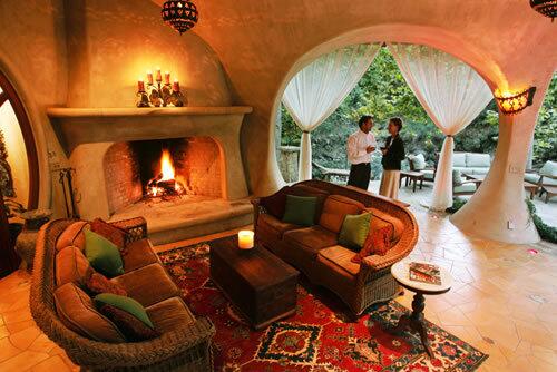 Julia and Marc Whitman are framed in the gathered, white drapes of the porch, with its pillars sculpted into the shapes of tree trunks. The floor is randomly scattered with inset tile leaves.