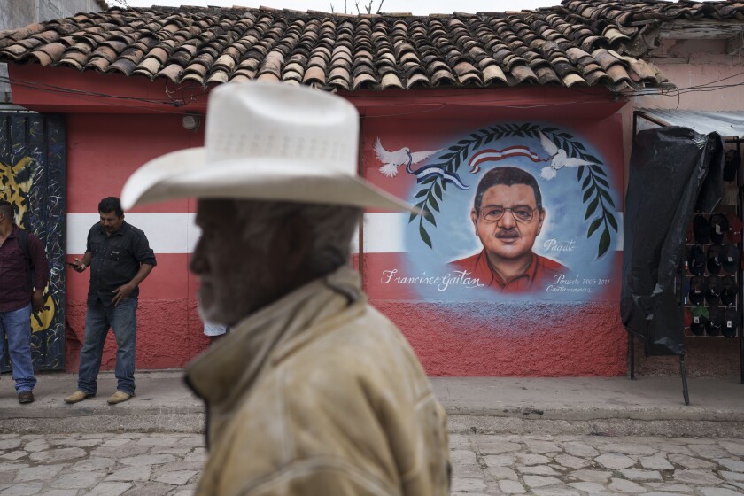 A man walks past a mural of the late Mayor Francisco Gaitan, painted on the facade of the Liberal Party headquarters in Cantarranas, Honduras, Saturday, Nov. 27, 2021, one day ahead of the general elections. Political related violence prior to Sunday’s elections has reached unprecedented levels with close to 30 murders considered to have been motivated by or involving politicians. Gaitan, who was seeking his fifth re-election as mayor of Cantarranas, was murdered on Nov. 13. (AP Photo/Moises Castillo)