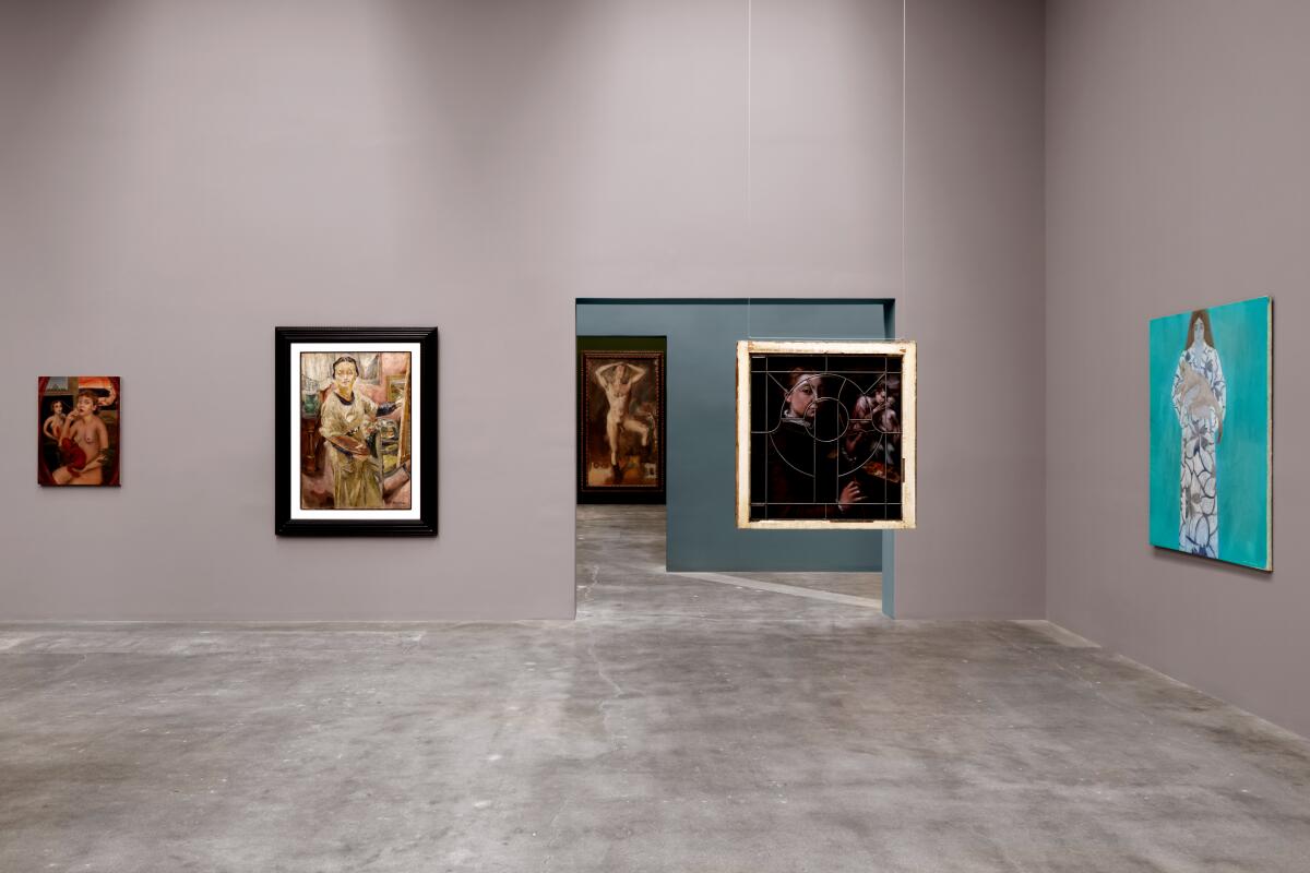 A gallery space with portraits on the wall and hanging from the ceiling.