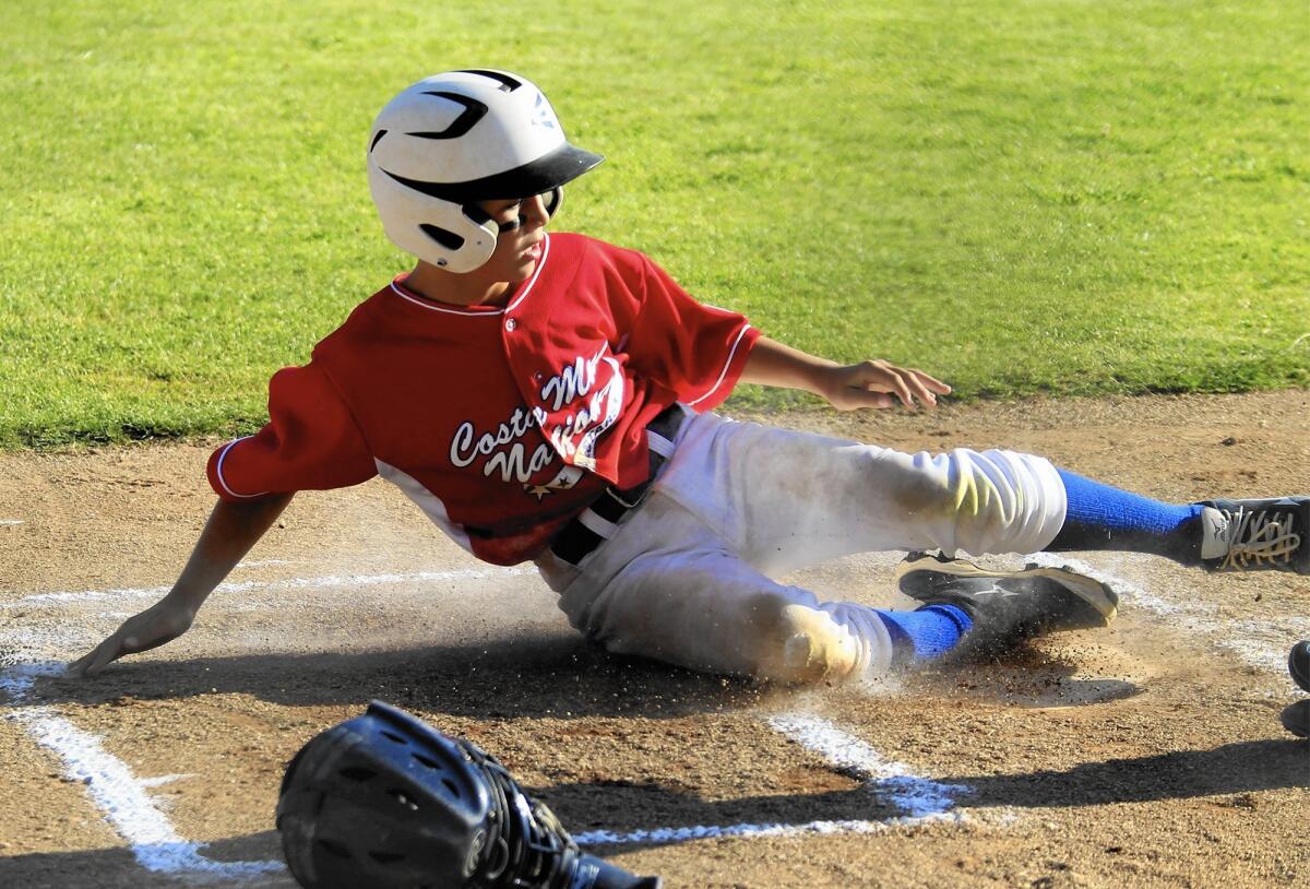 Costa Mesa National Little League's Grant L'Heureux slides into home during a 2014 game at TeWinkle Middle School, one of the city's locations with permanent lighting.