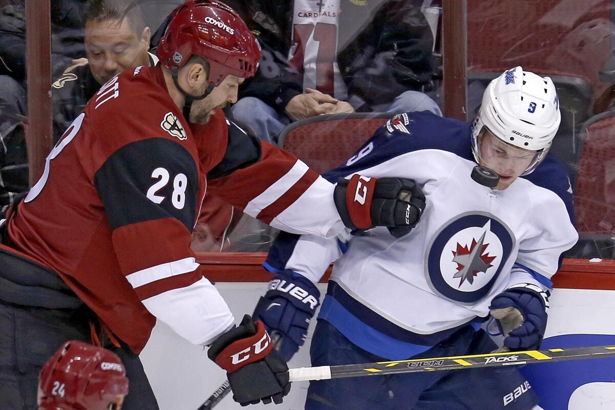 Arizona's John Scott, left, and Winnipeg's Andrew Copp battle for the puck on Dec. 31.