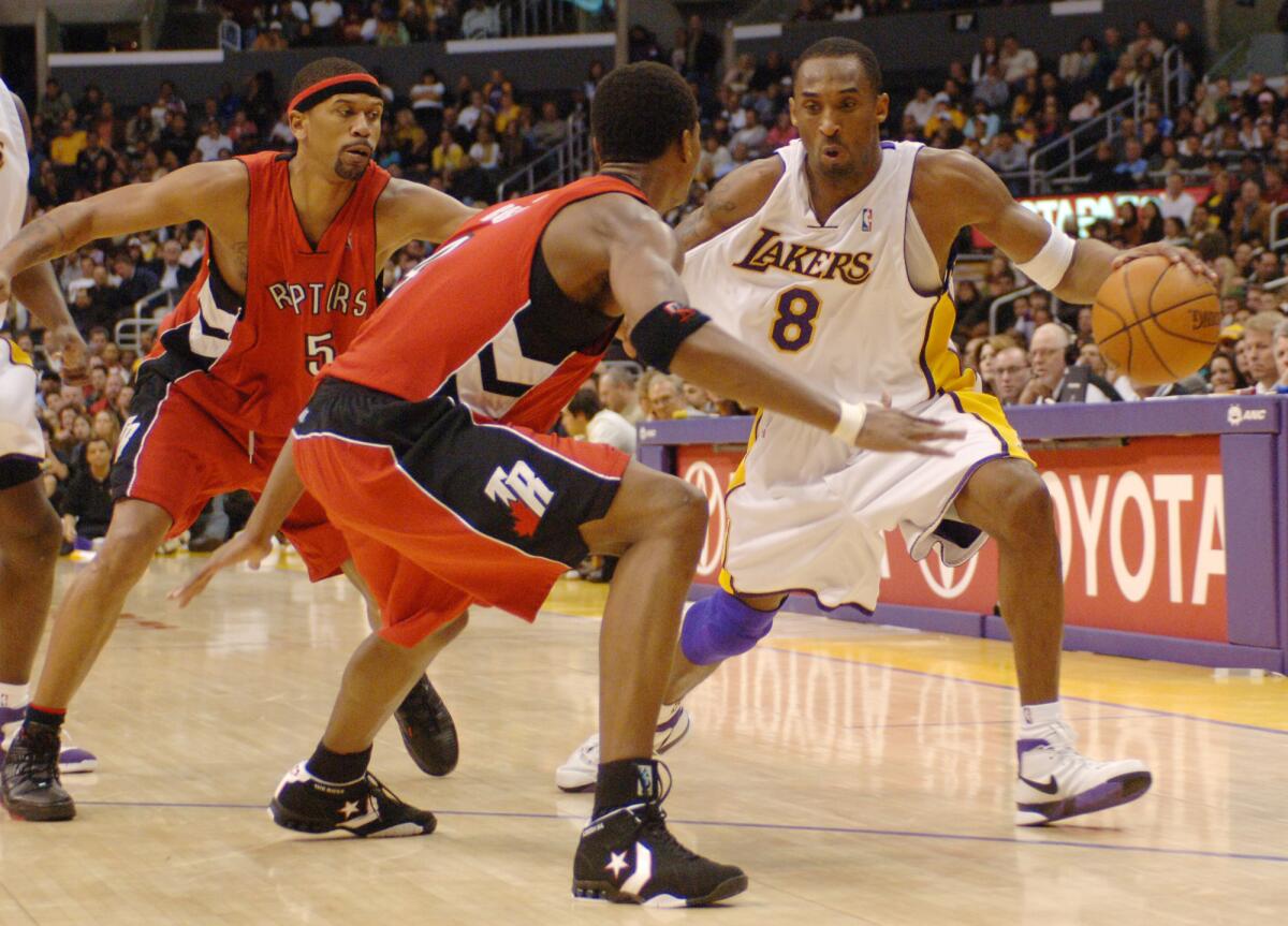 Lakers' Kobe Bryant drives past Toronto Raptors' Jalen Rose and Chris Bosh.