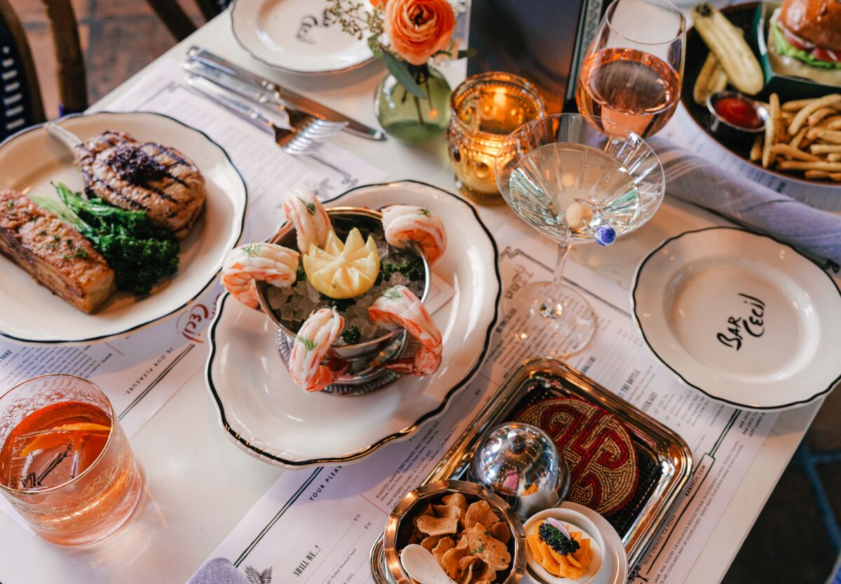 Dishes on a table at Bar Cecil include roast chicken, shrimp cocktail and a martini.