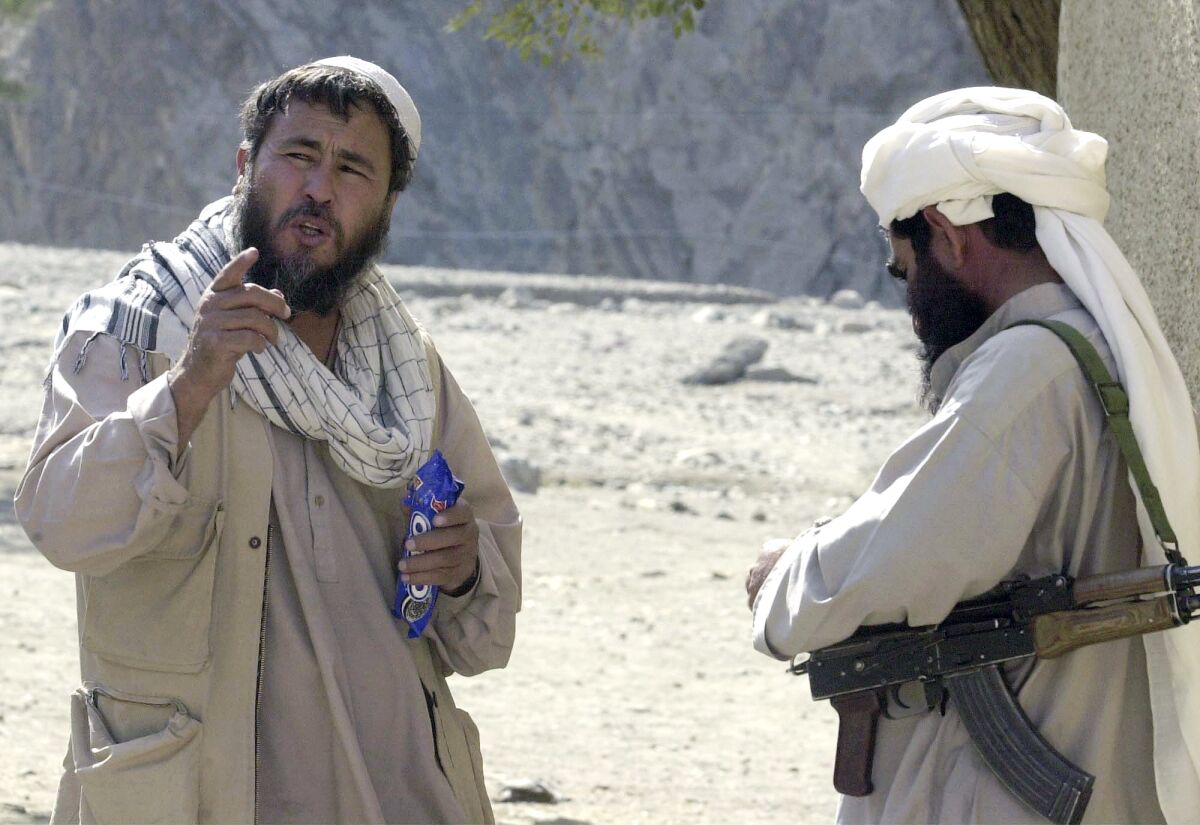 FILE - In this Wednesday, Oct. 24, 2001 file photo, Associated Press correspondent Amir Shah, left, talks with a Taliban fighter in Torkham, Afghanistan. Shah was AP's eyes and ears in Afghanistan after the 9/11 attacks, when all foreigners were ordered to leave. His assignment was dangerous, delicate and often terrifying. (AP Photo/Dimitri Messinis, File)