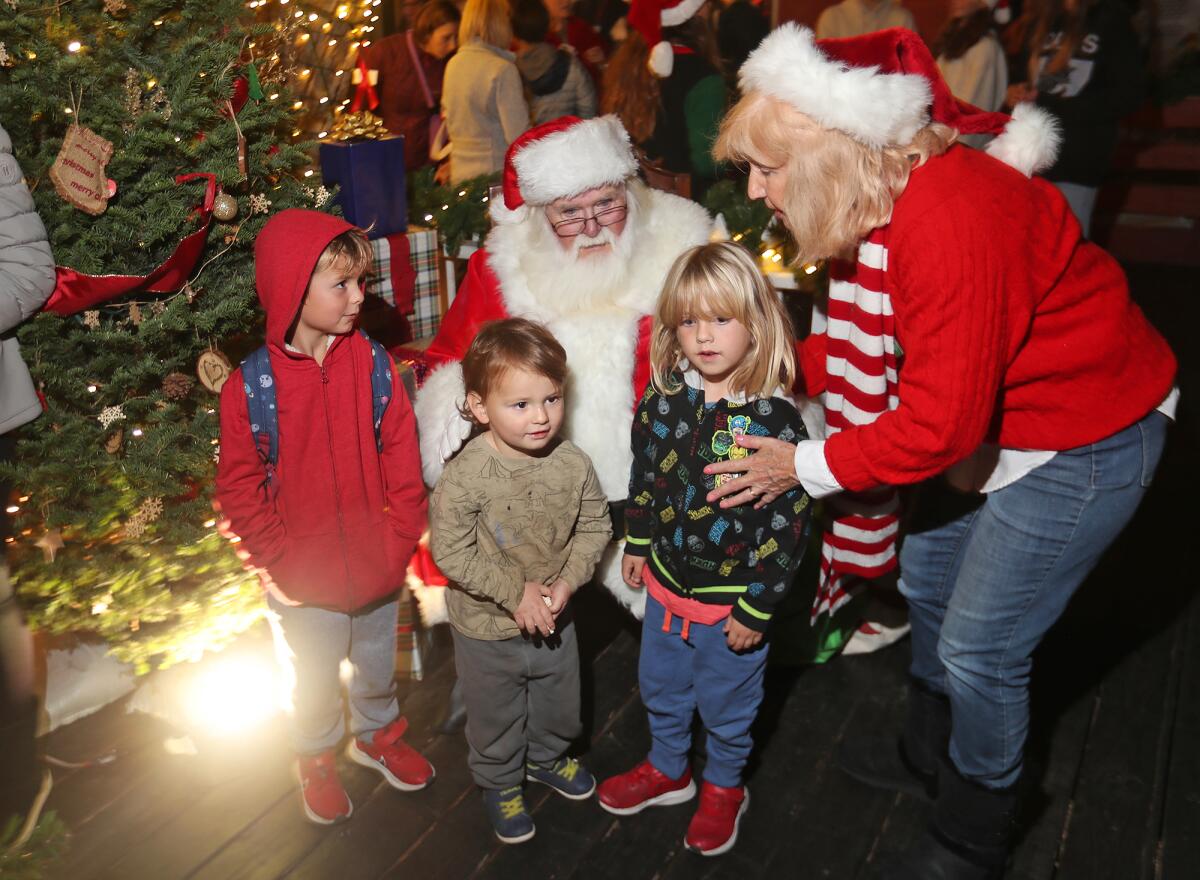 Sande St. John, right, gets kids together for a photo with Santa, during Hospitality Night in downtown Laguna Beach.