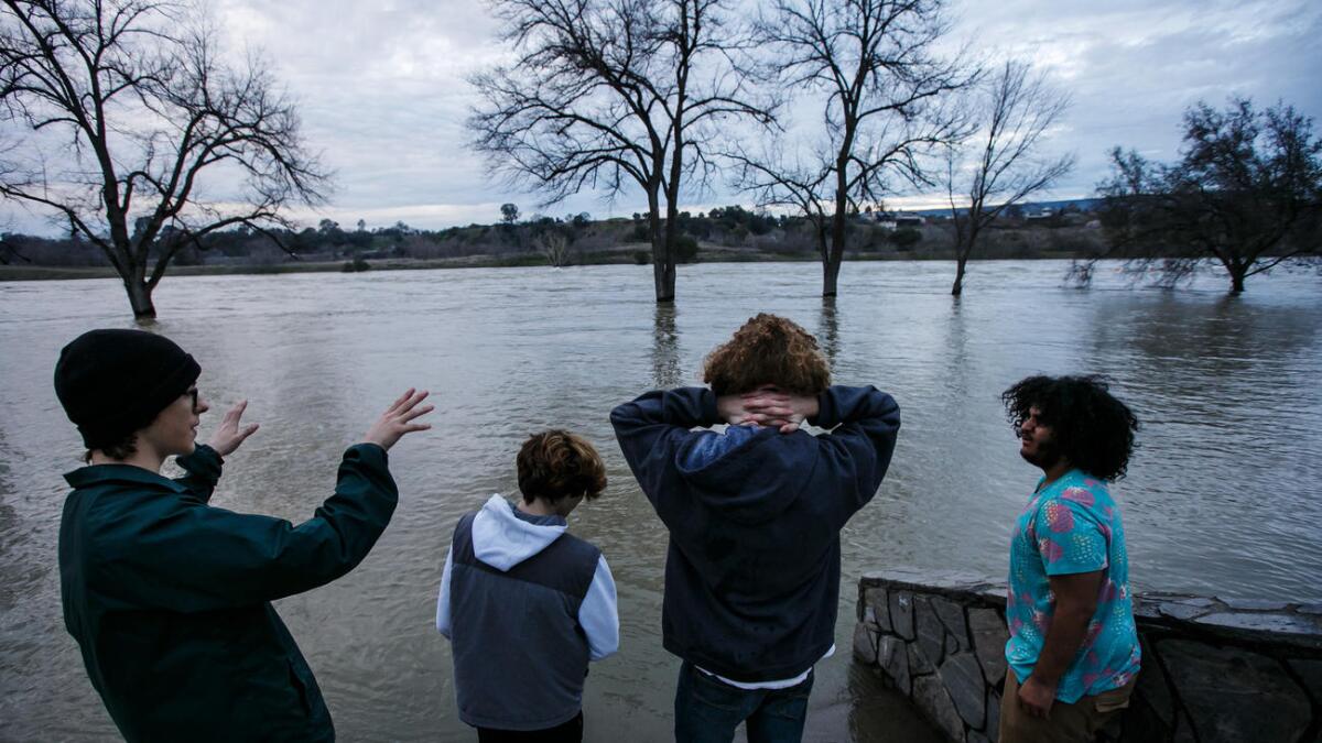 Friends Johnny Eroh, from left, Cody Balmer, Kristien Bravo and Jerel Bruhn hang out by the swollen Feather River in Oroville.