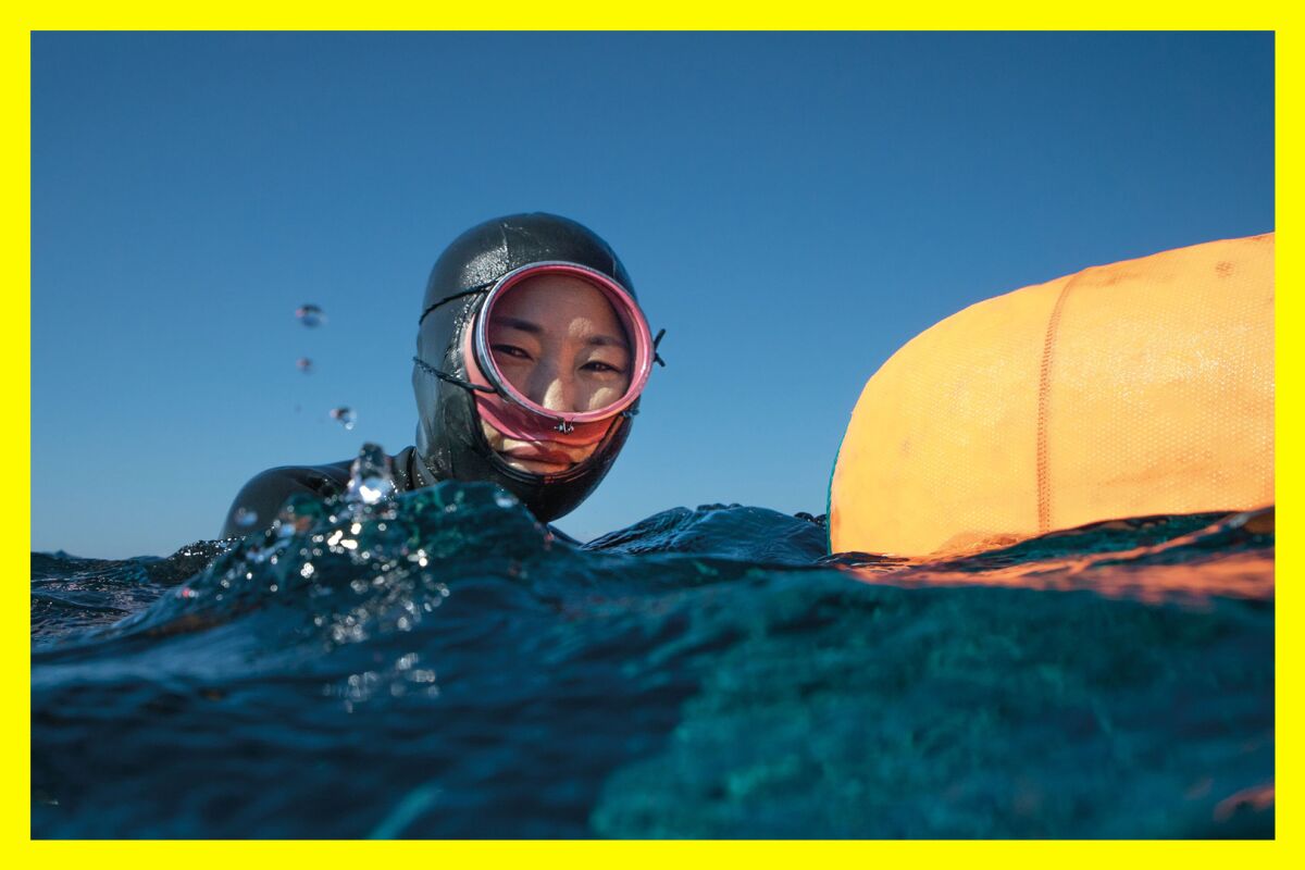 A woman wears a wet suit and face mask while floating in water