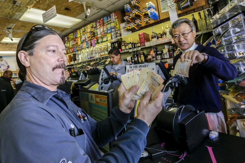 Mark Nelson, left, shows off $460 worth of Powerball lottery tickets he bought at Bluebird Liquor, a shop with a reputation for lottery luck, in Hawthorne. At right is the owner of the liquor store, James Kim.