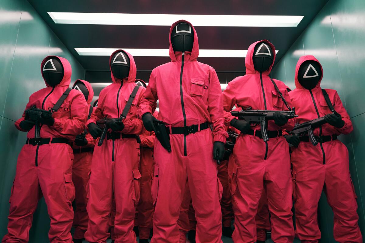 Gun-toting masked figures in pink track suits 