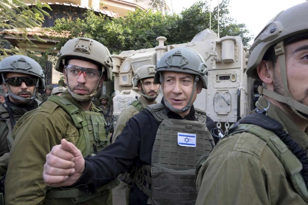 Benjamin Netanyahu wears a helmet and gives a thumbs-up to Israeli troops.