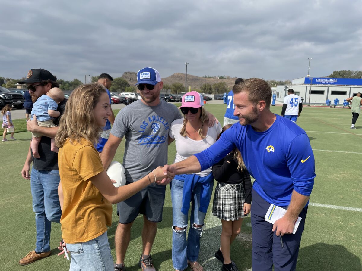 Rams coach Sean McVay shakes hands with a family member of the late Carter Stone while other people look on.