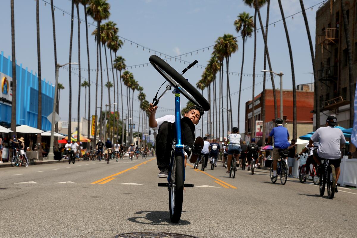A teenager pops a wheelie on Avalon Boulevard in Wilmington during CicLAvia in August 2021. 