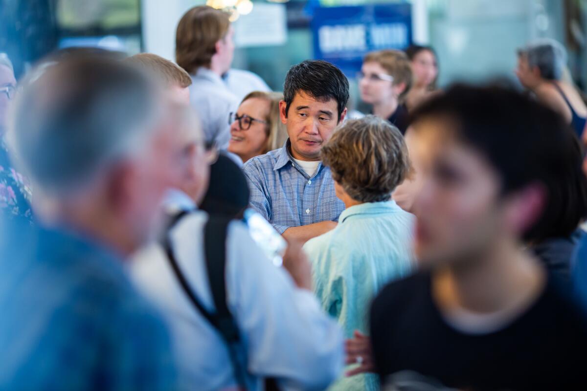 Dave Min talks with his supporters during a campaign event.