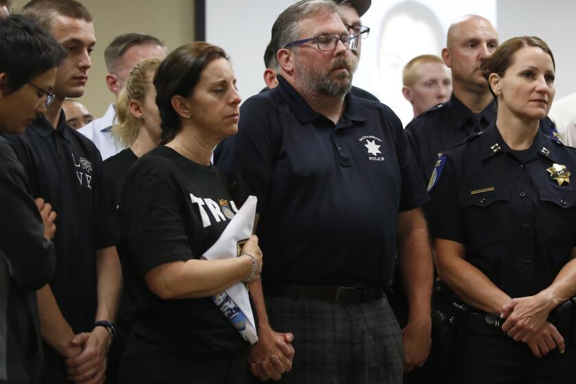 With their eyes closed, Kelly and Denis O'Sullivan, the parents of slain Sacramento Police officer Tara O'Sullivan, hold hands during a news conference in Sacramento, Calif., Tuesday, June 25, 2019. Denis O'Sullivan told the media that any notion that the Sacramento Police Department was responsible for her death was extremely offensive and hurtful. It took rescuers 45 minutes to reach Tara O'Sullivan after she was shot by gunman, who kept shooting at police, during a domestic violence call last week. (AP Photo/Rich Pedroncelli)