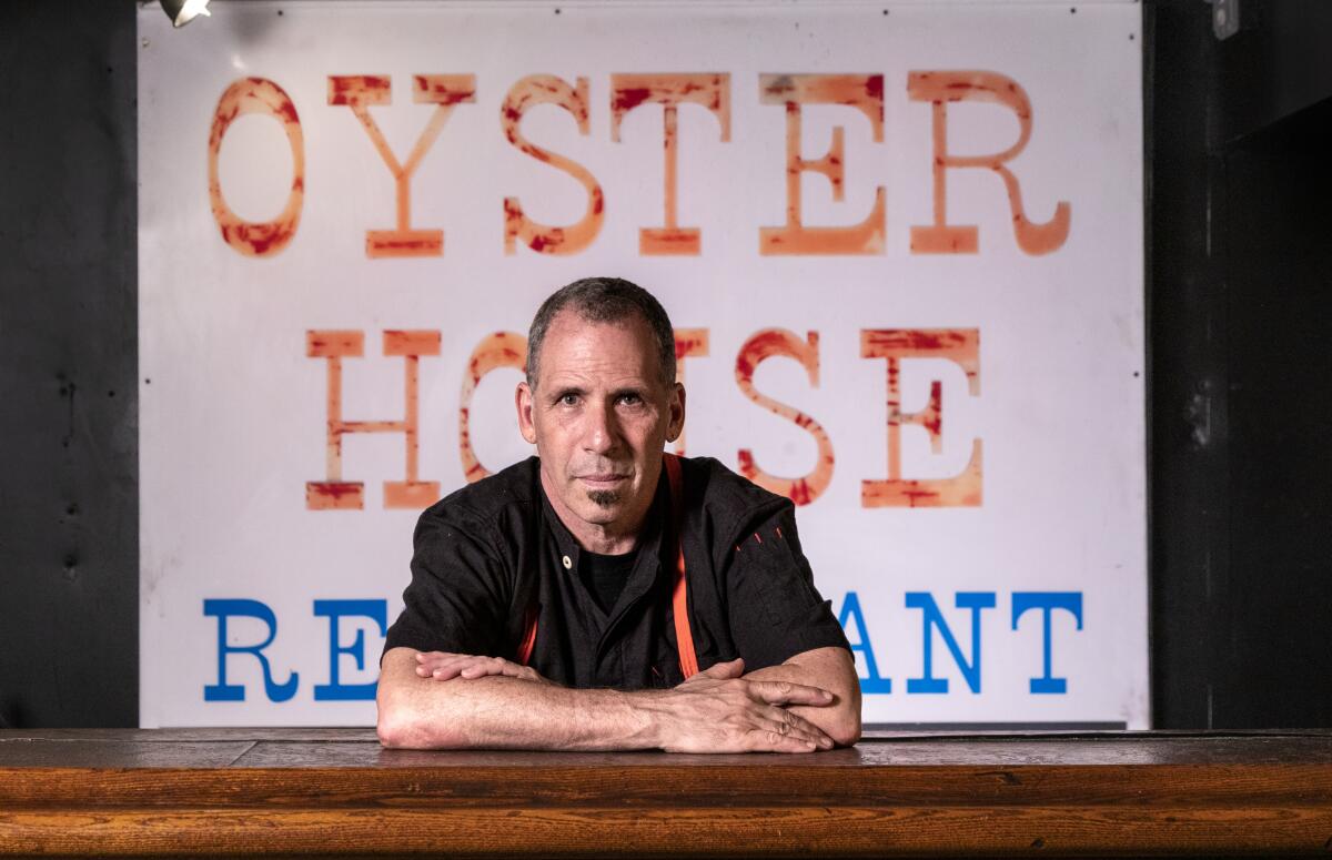 Oy Bar owner Jeff Strauss, in a black shirt, in front of a sign that reads OYSTER HOUSE RESTAURANT