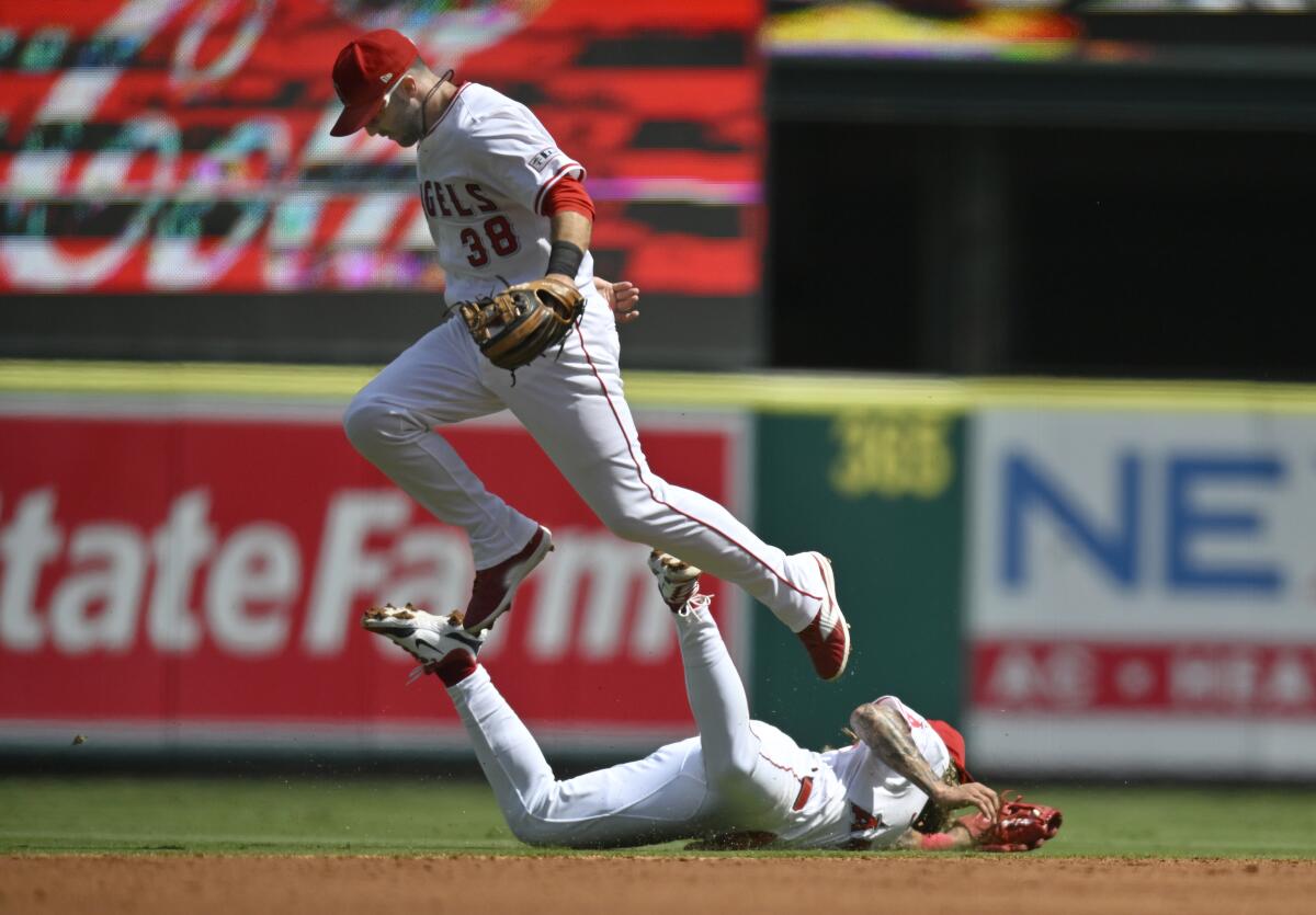 A baseball player jumps over a diving player.