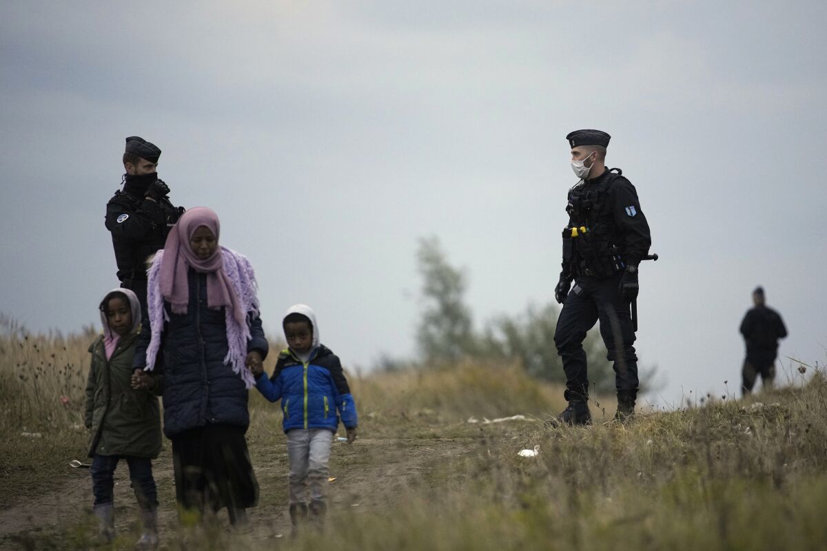 FILE - Police officers patrol near a migrant camp in Calais, northern France, Thursday, Oct. 14, 2021. Thousands of migrants have converged in northern France near the area of the former makeshift camp known as "The Jungle", with an aim to traverse the English Channel and reach the U.K., French media reported Monday. (AP Photo/Christophe Ena, File)