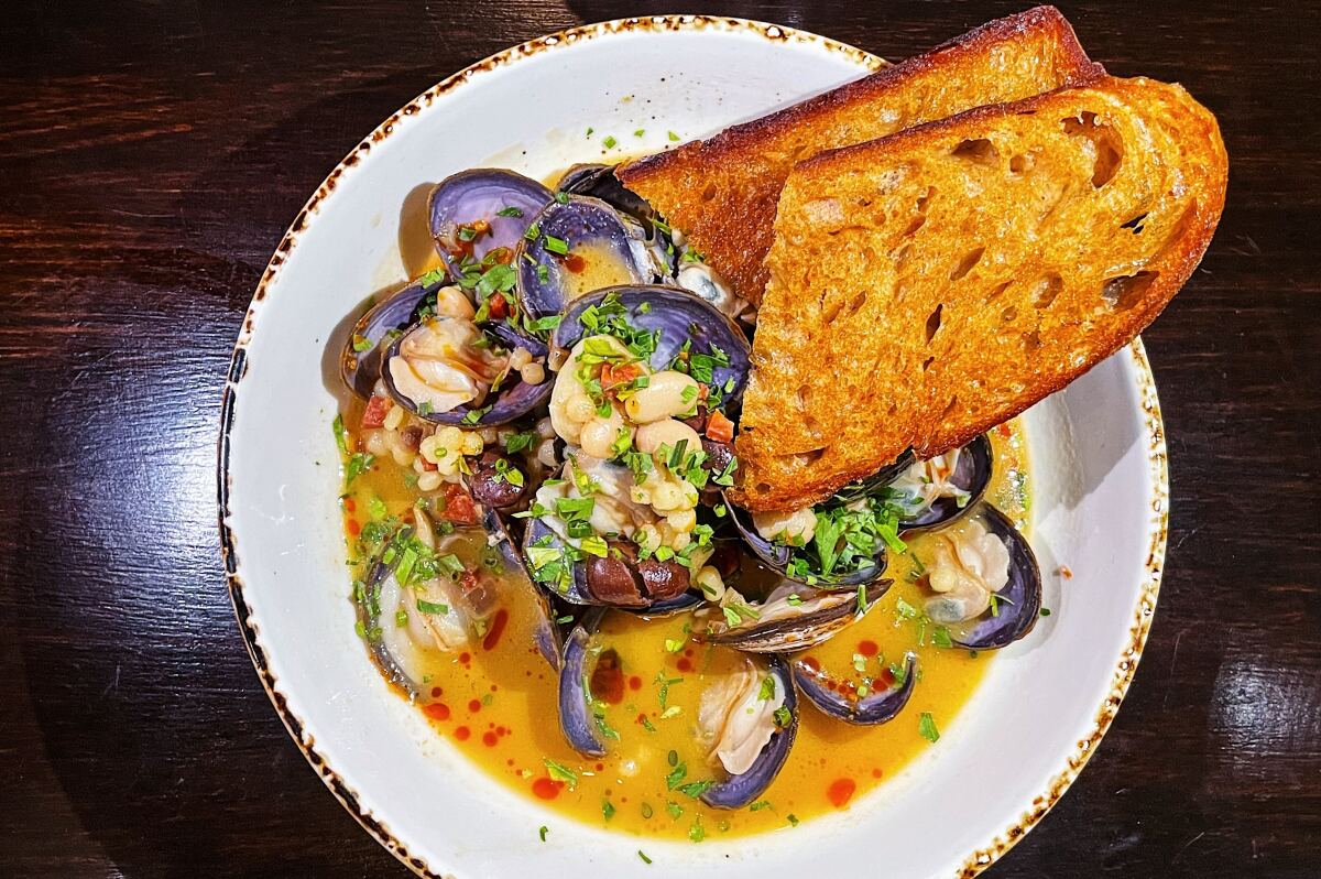 An overhead photo of clams and chorizo with fregula and beans at Highland Park's Amiga Amore