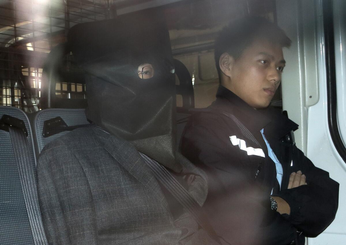 Chinese fugitive Shi Deyun, his face hidden under a hood, in police custody following his arrest after arriving in Hong Kong on a flight from Los Angeles on Jan. 25, 2016.