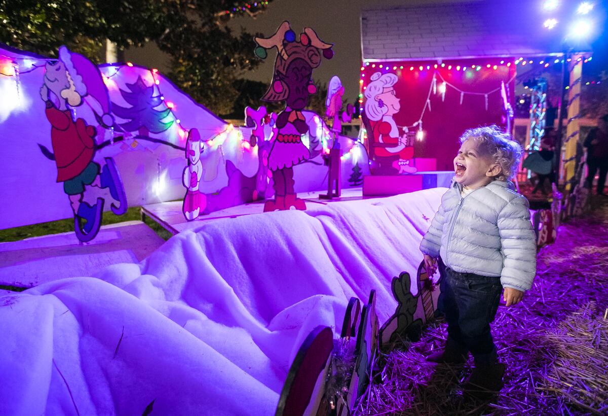 A child laughs while viewing the 2019 Snoopy House holiday display at Costa Mesa City Hall.
