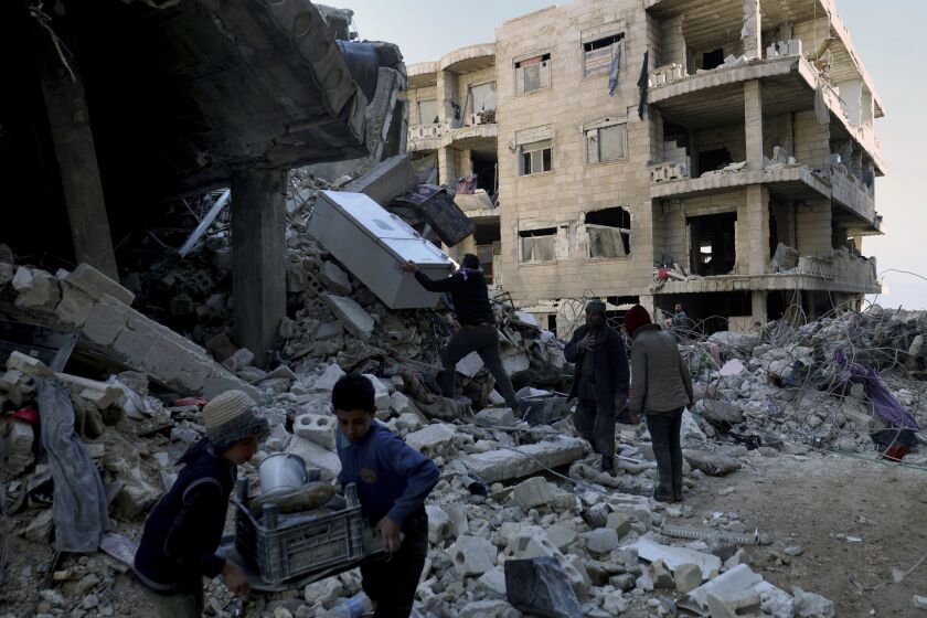 People remove furniture and household appliances out of a collapsed building after a devastating earthquake rocked Syria and Turkey in the town of Jinderis, Aleppo province, Syria, Tuesday, Feb. 7, 2023. The quake has brought down thousands of buildings and killed thousands of people. In Syria, it also came on the heels of over a decade of conflict and a crippling economic crisis. (AP Photo/Ghaith Alsayed)