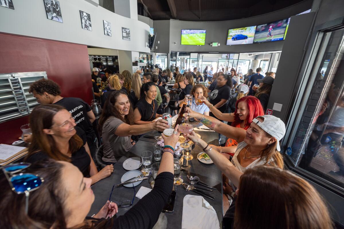 Goście wznoszą toast podczas oglądania kobiecych zawodów sportowych podczas wielkiego otwarcia Watch Me! Sports Bar w Long Beach.