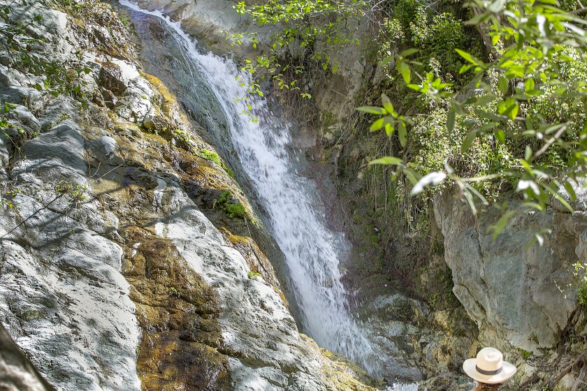 A woman sits on a rock and views the Monrovia Canyon Falls